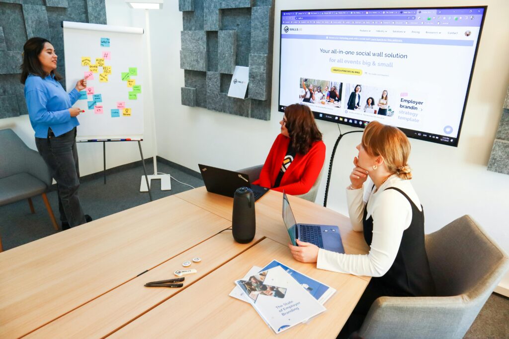 Three women collaborate in a conference room using digital tools for effective teamwork.